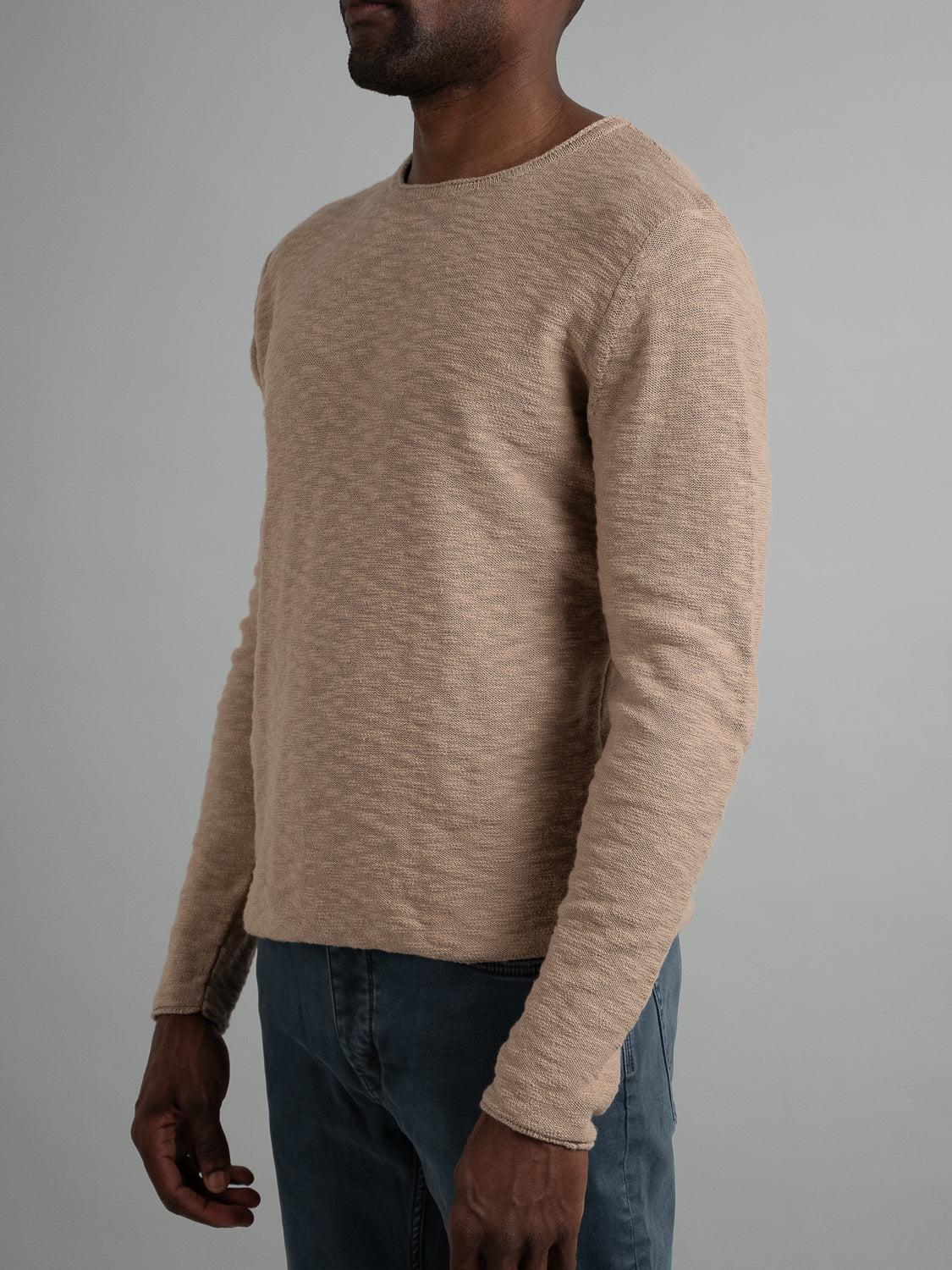 Someone wearing an ID Menswear Havana Slub Yarn Sweater Tee in beige with dark blue pants, exuding casual vibes against a plain gray background, offering a premium feel.