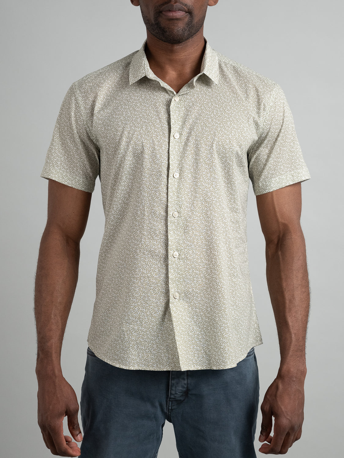 A person models ID Menswears Anise Short Sleeve Cotton Printed Shirt, exhibiting a sleek, slim-fit design and intricate pattern. Paired with dark pants against a plain gray background, they face forward with arms relaxed, highlighting the outfits clean lines.