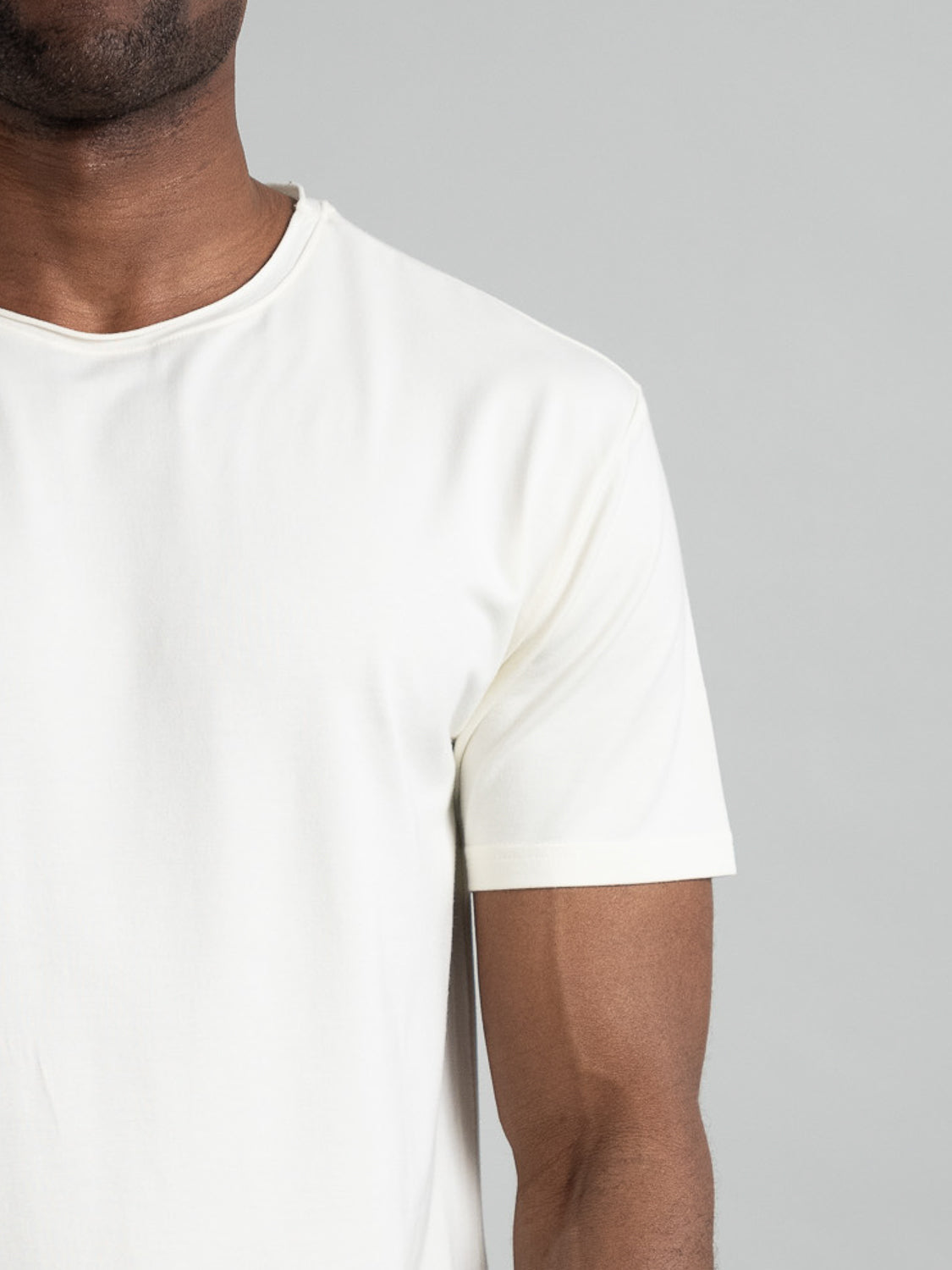 A person in an ID Menswear Bello Bamboo Blend Rolled Neck Tee is captured against a light gray background, emphasizing sustainable clothing.