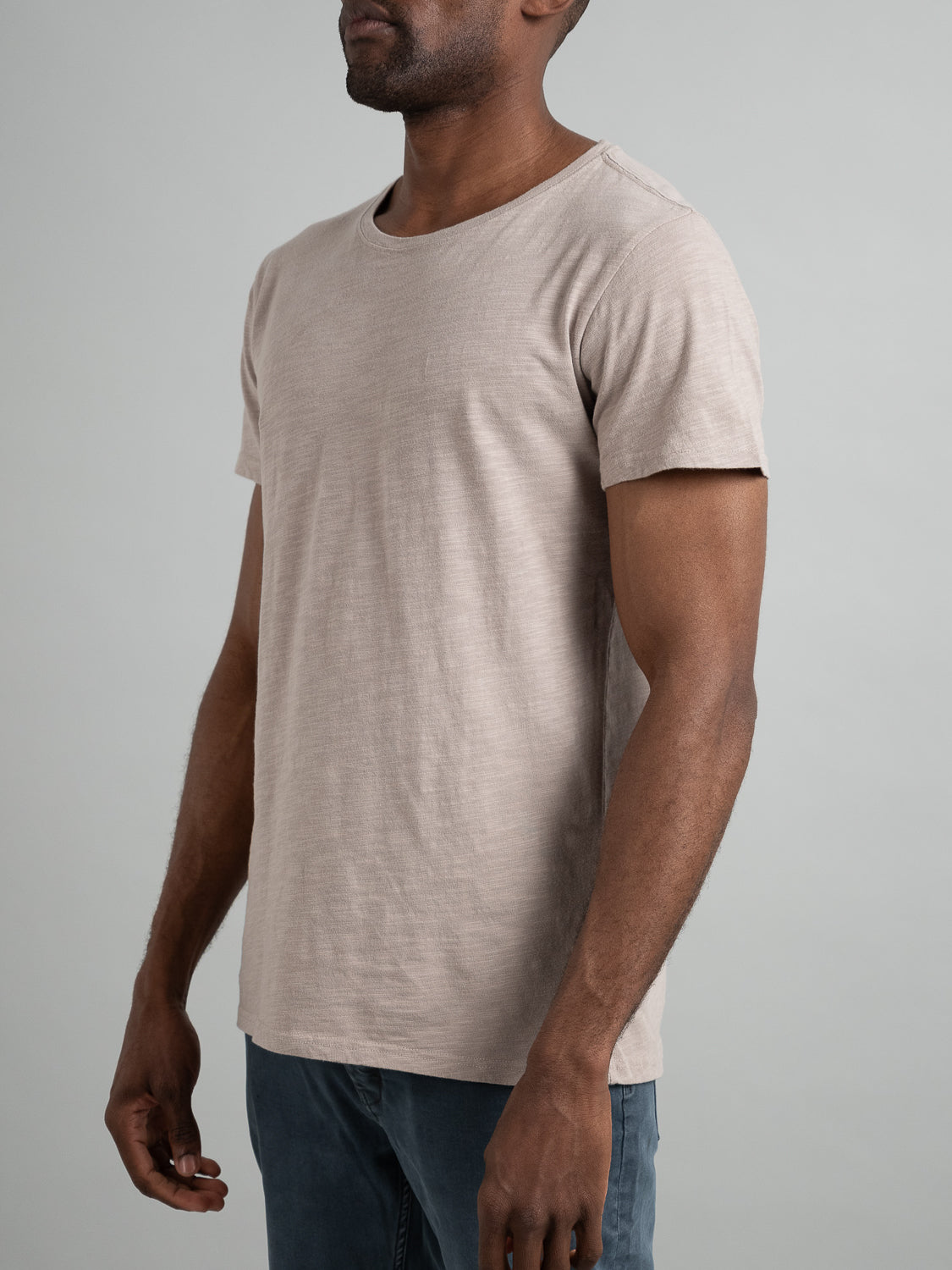 A person wearing the ID Menswear Mini Flip Slub Yarn Tee and blue jeans stands against a neutral background, focused from shoulders down with arms relaxed, perfectly capturing an effortless casual look.