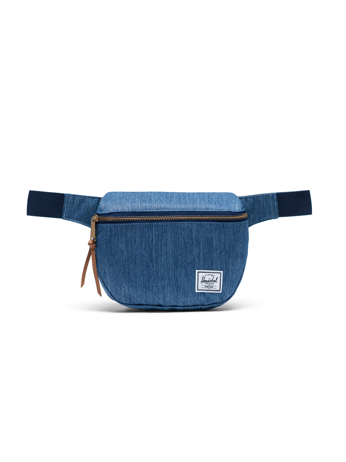 The Herschel Fifteen Hip Pack features blue denim fabric, an adjustable strap, a brown metal zipper, and a small white rectangular logo patch on the front, shown against a plain white background.