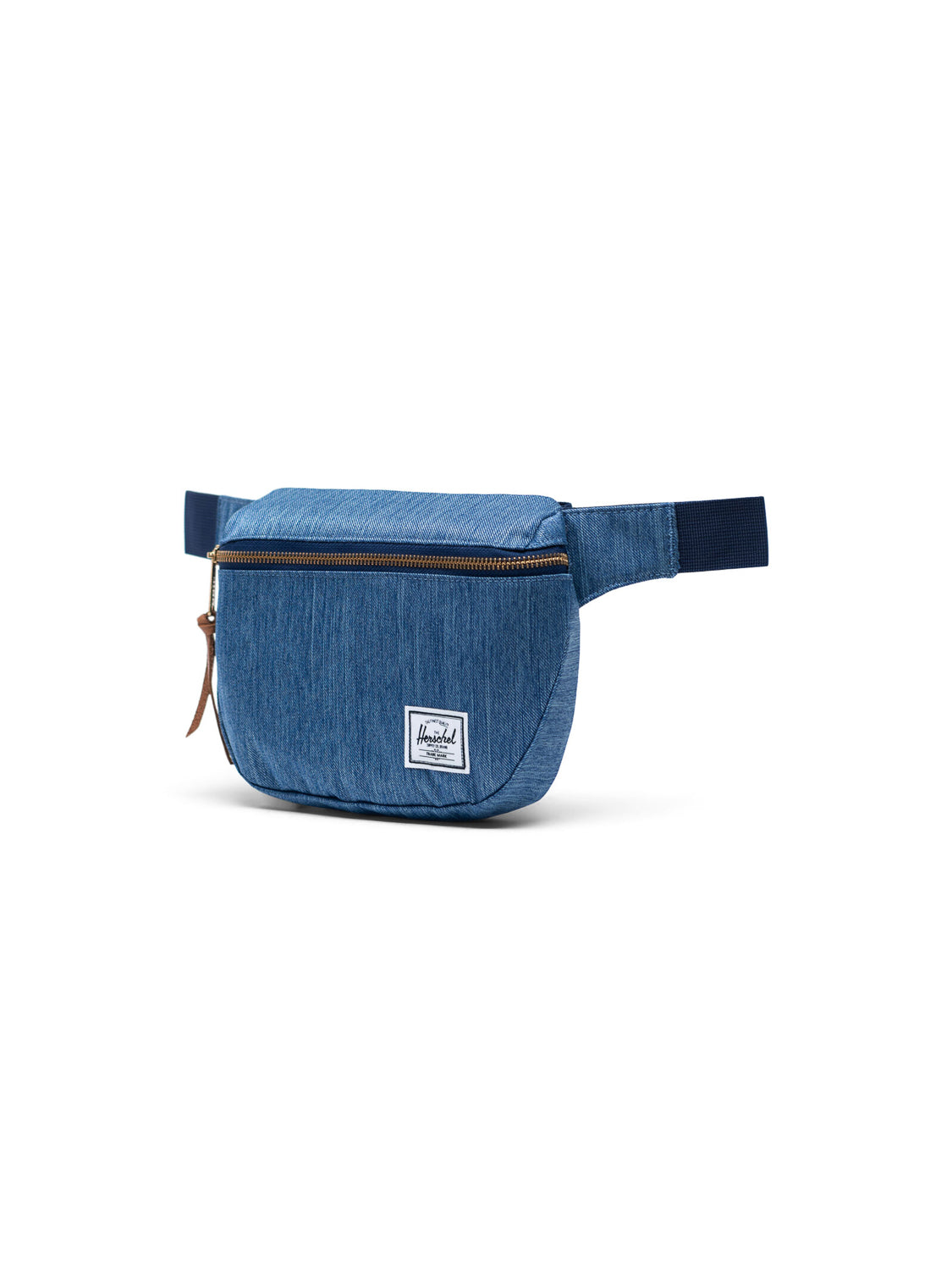 The Herschel Fifteen Hip Pack features blue denim fabric, a metal zipper, brown leather pull, adjustable strap, and a white logo patch on the lower front.