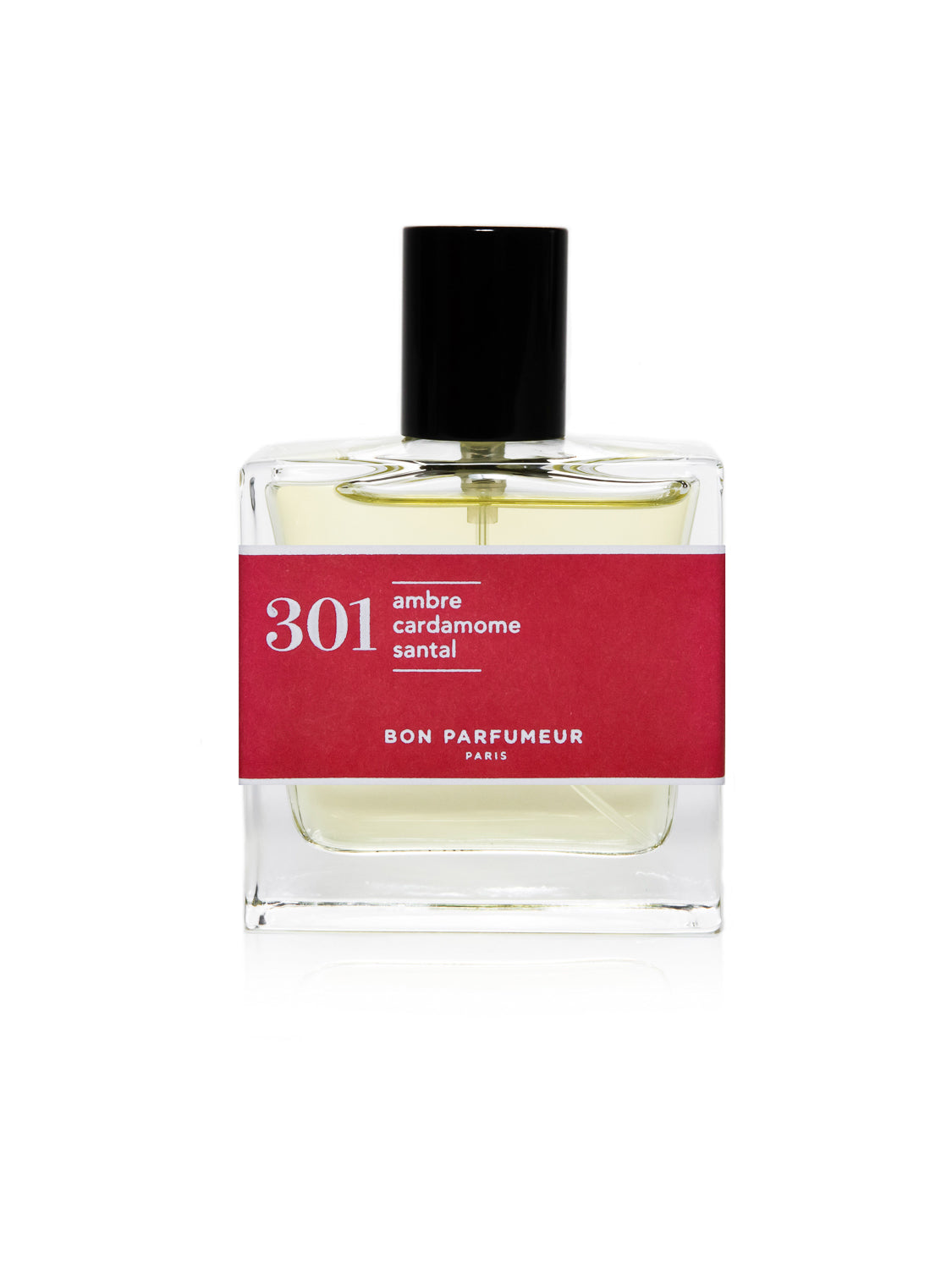 A clear glass bottle with a black cap and red label reads Bon Parfumeur Paris, 301 ambre cardamome santal. Filled with light yellow liquid, it exudes spicy amber aromas intertwined with jasmine and sandalwood.