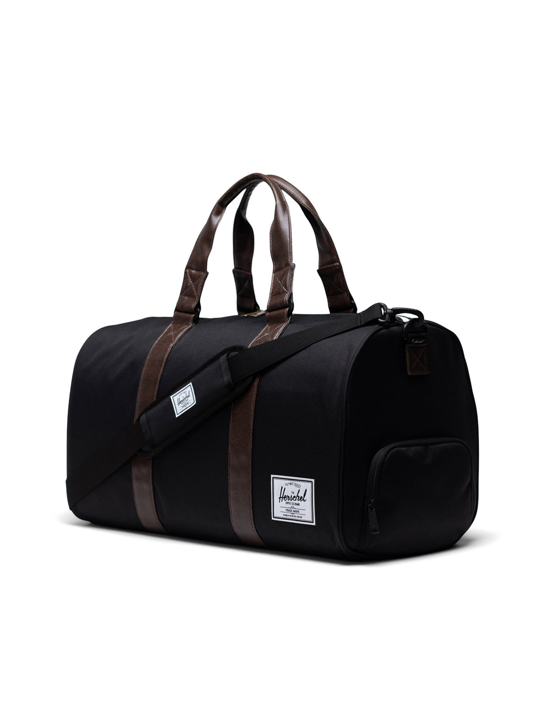 A black Herschel Novel Weekender Duffle Bag with brown handles, a detachable shoulder strap, a white rectangular label, and a zippered end pocket featuring a dedicated shoe compartment on a white background.