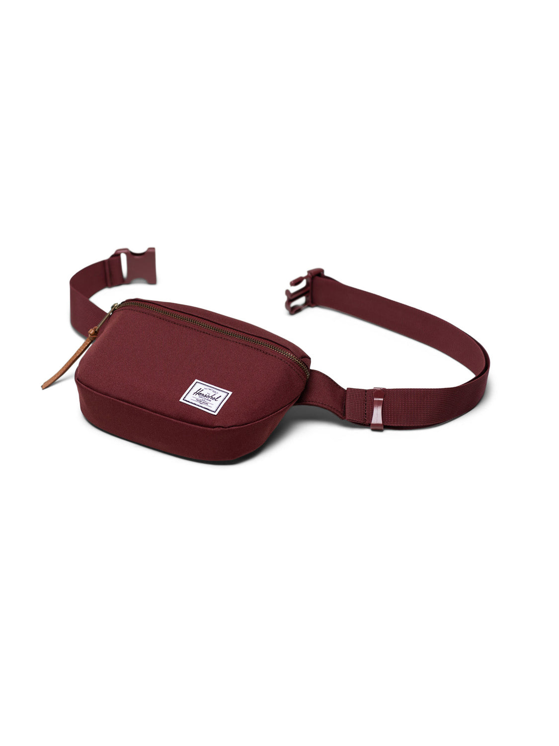 The Herschel Fifteen Hip Pack is maroon, featuring a zippered main compartment, adjustable strap with plastic buckle, and a white rectangular logo patch on the front for style and secure fit.