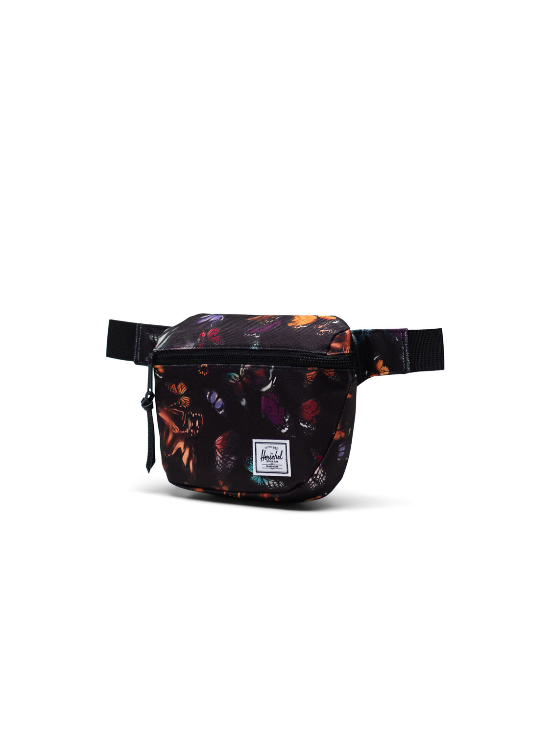 The Herschel Fifteen Hip Pack features a colorful butterfly print on black, a front metal zipper pocket, and an adjustable strap, shown against a white background.
