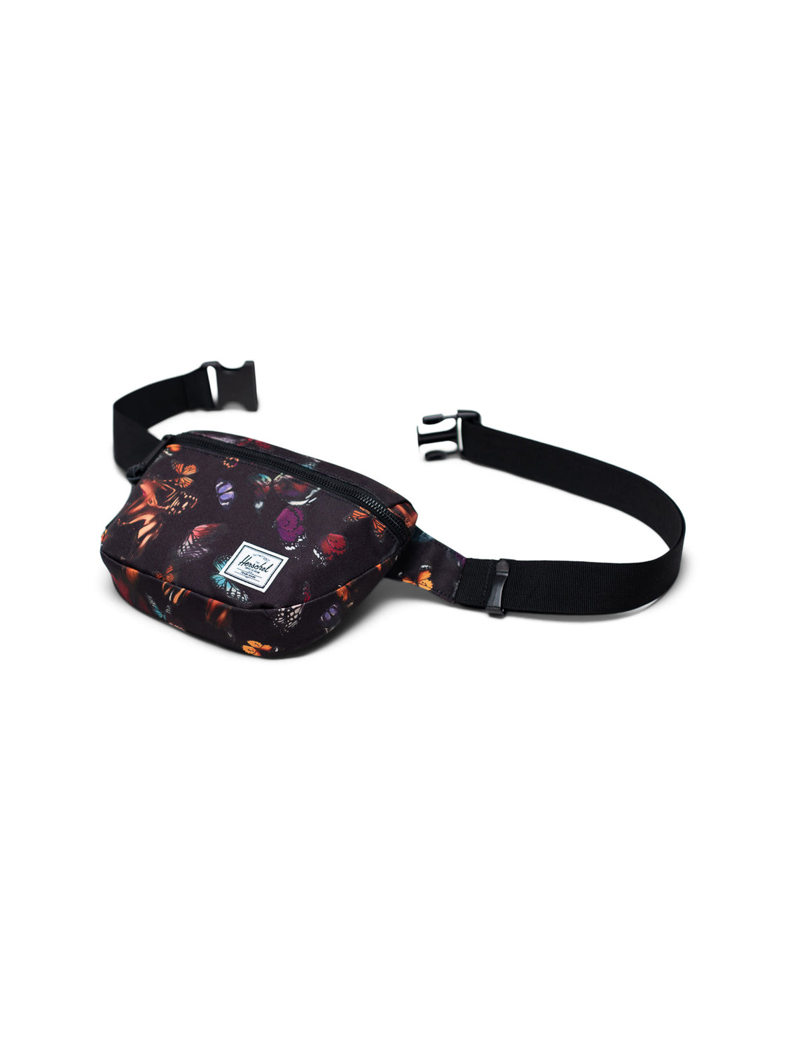 The Herschel Fifteen Hip Pack features a black base with a vibrant floral pattern in orange, red, and purple, a small white front label, metal zipper closure, and an adjustable black strap with a plastic buckle.