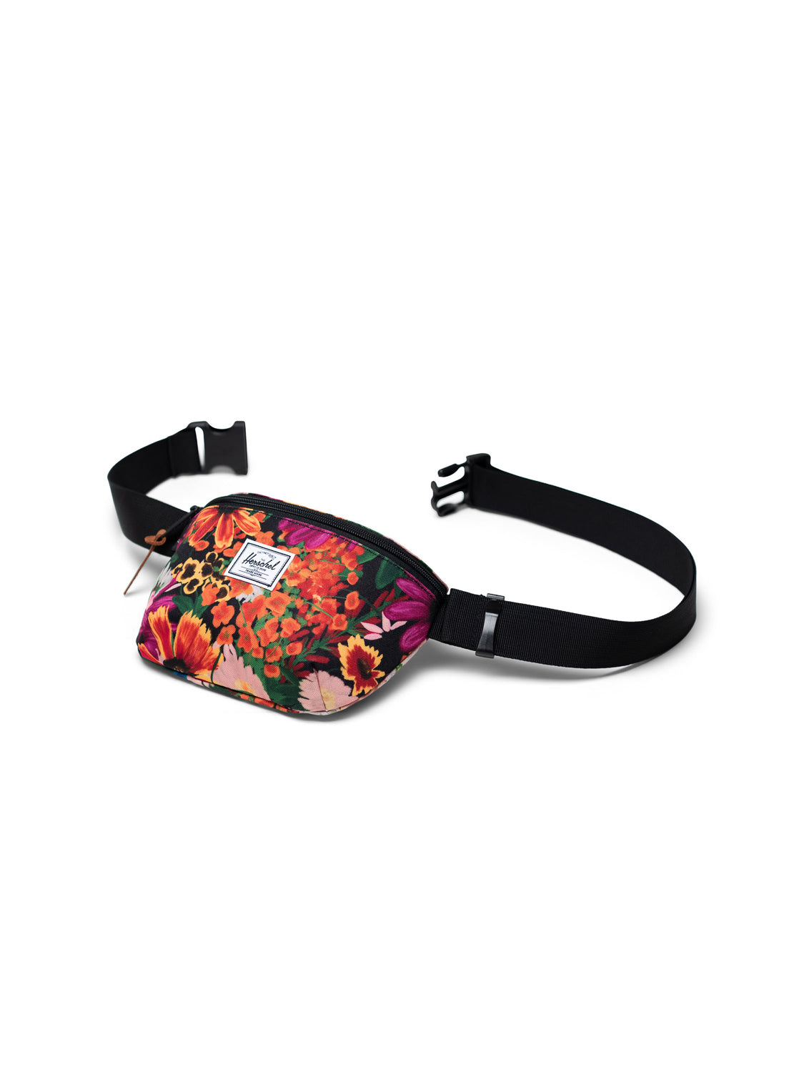 The Herschel Fourteen Hip Pack is a colorful floral-patterned essentials bag with a black adjustable strap, plastic buckle, zippered main compartment, and a white rectangular logo patch on the front, shown on a white background.