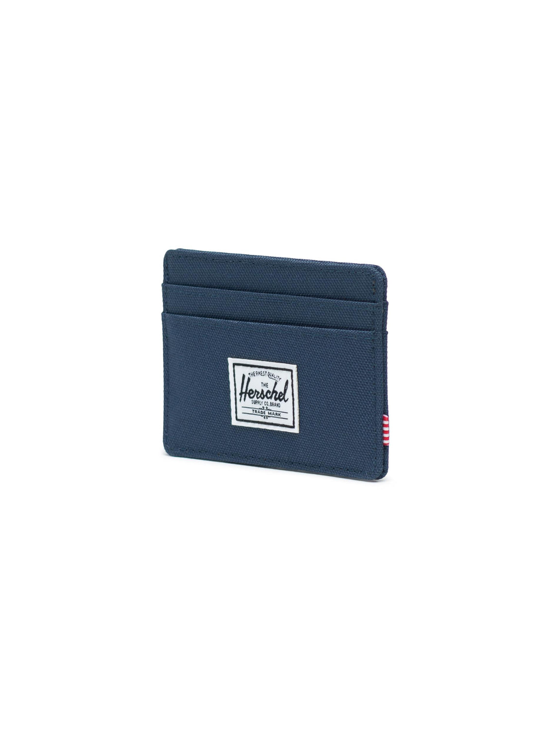 The Herschel Charlie Compact Card Holder Wallet is a navy blue RFID-blocking wallet with two card slots, a white sewn-on logo patch on the front, and a small red and white striped side tag.