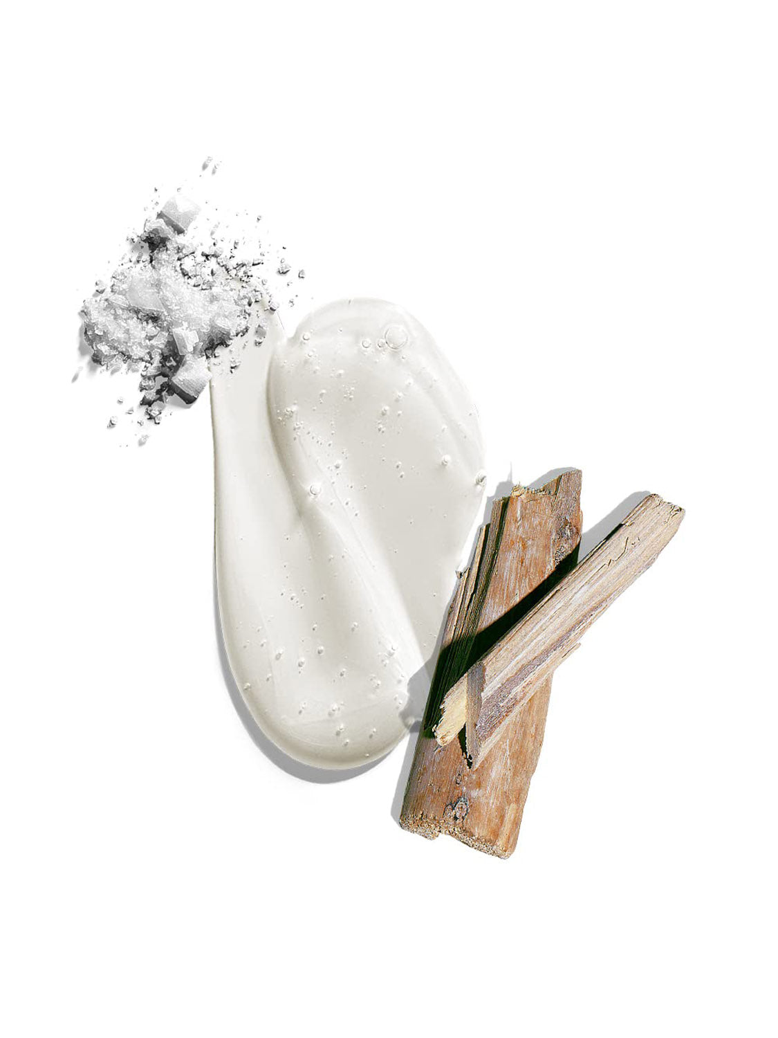 A smear of creamy white lotion, fine white powder, and two pieces of light brown wood are shown on a white background, highlighting the fresh appeal of Jack Black’s Body and Hair Cleanser.