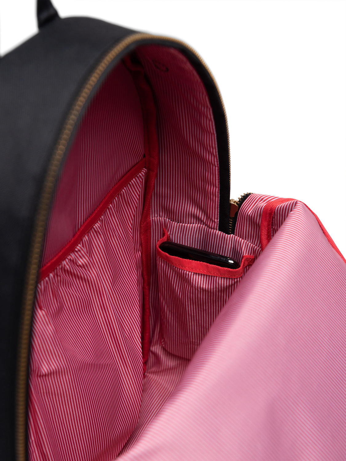 The image shows the interior of the Herschel Settlement Backpack, featuring a red and white striped lining, multiple inner pockets including a laptop sleeve, and a smartphone in one pocket. The backpack’s exterior is black.