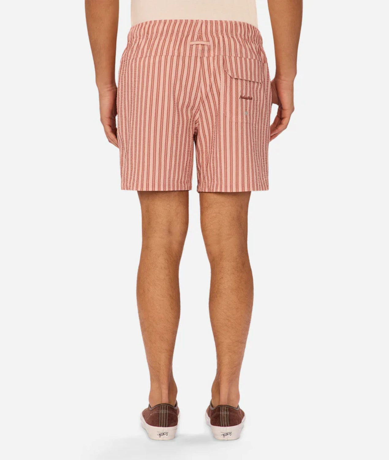 Back view of a person wearing Industrie Berkeley Swim Shorts in red and white vertical stripes with brown slip-on shoes, standing against a plain white background.