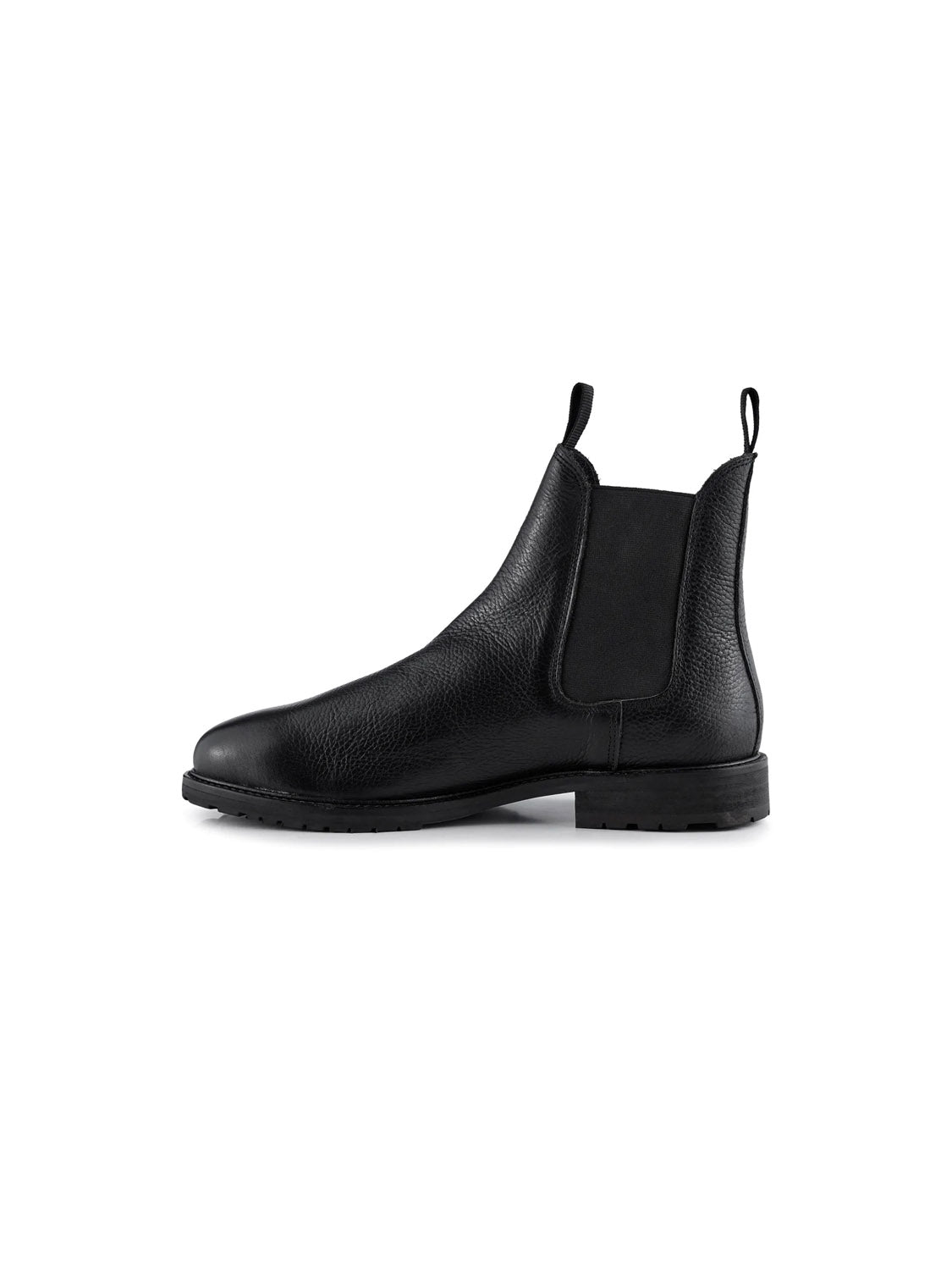 The York Classic Chelsea Boot by Shoe The Bear is depicted in profile, showcasing its smooth LWG-certified black leather texture. It includes elastic side panels, a back pull tab, and a dark sturdy rubber outsole for a sleek, classic look.