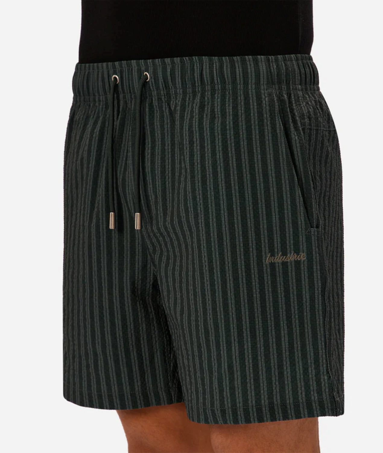Someone wearing Industrie’s Berkeley Swim Short—dark green with vertical stripes, an elastic waistband, drawstrings, side pockets, and "balistier" embroidered on the left leg.