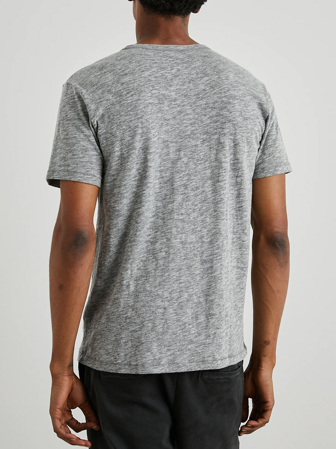 Rear view of a person wearing the Rails Skipper Tee, a gray marled short-sleeve T-shirt with a vintage wash, paired with black pants against a light gray background.