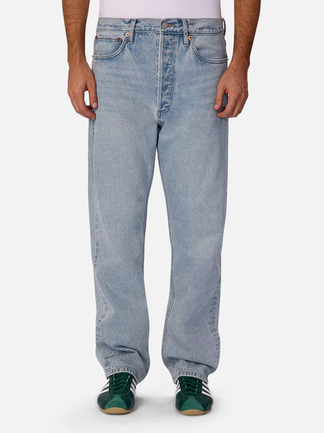 A person wearing Industrie 90s Jean Stone Wash straight-leg jeans, a white shirt, and green sneakers stands against a plain white background.