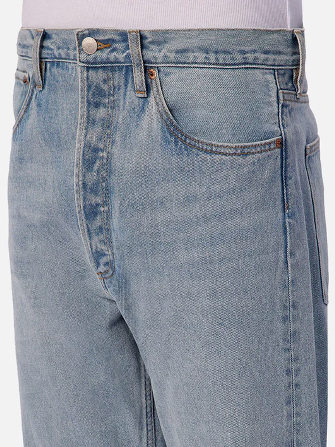 Close-up of a person wearing Industrie 90s Jean Stone Wash—light blue straight leg jeans with a classic five-pocket design and vintage wash—paired with a tucked-in white shirt.
