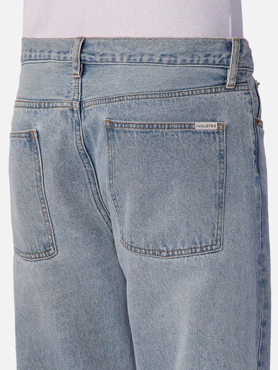 Close-up of the back of a person wearing Industrie 90s Jean Stone Wash and a white top, featuring two back pockets and a small white label on the waistband.