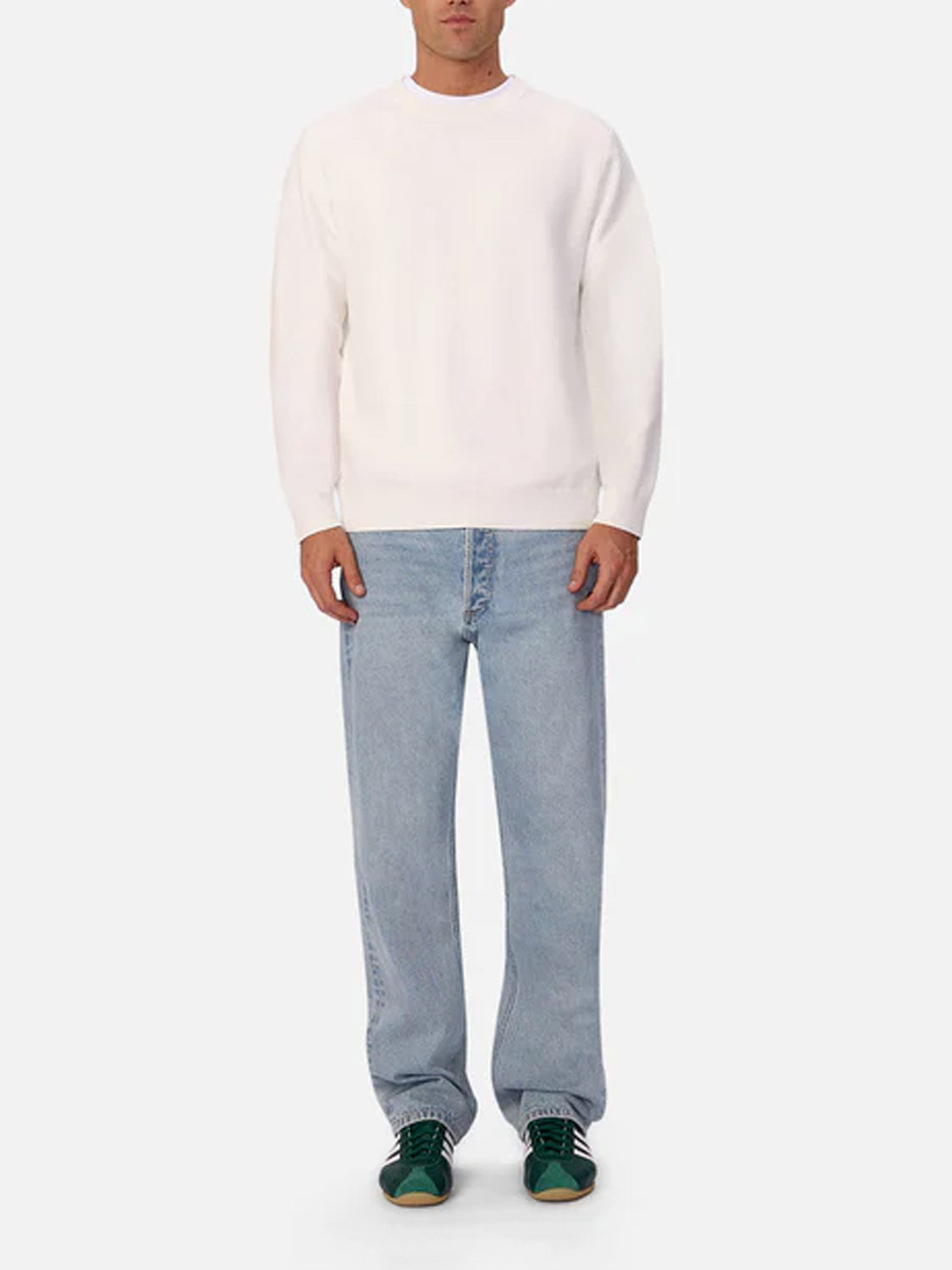 A person wears a plain white long-sleeve sweatshirt, Industrie 90s Jean Stone Wash, and green sneakers, standing facing forward against a plain light background.