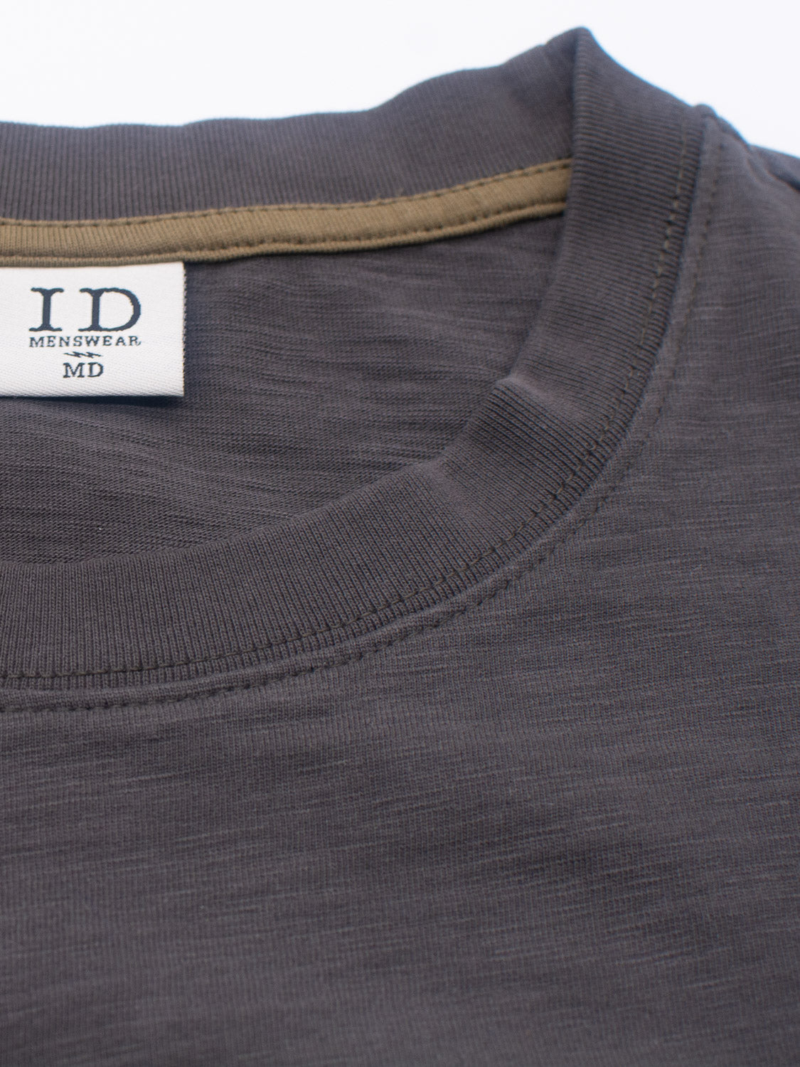 A close-up reveals the ID Menswear label on the Big Flip Slub Yarn Cotton Tee. This 100% cotton, gray T-shirt with a light brown inner neckline features a round collar and boxy fit, combining comfort with style.