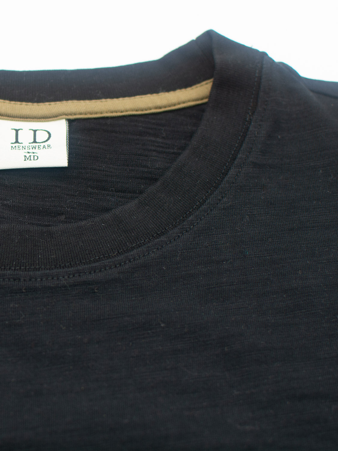 Close-up of the Big Flip Slub Yarn Cotton Tee by ID Menswear, showcasing a black crew neck made from 100% cotton. The visible inside label displays ID Menswear alongside a glimpse of the beige inner lining, emphasizing its comfortable boxy fit.