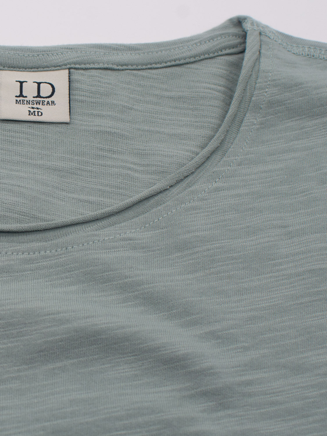 The Da Nang Rolled Neck Slub Tee by ID Menswear is a light green T-shirt with a comfortable, casual vibe. It features a round neckline, an inner label reading ID Menswear MD, and a slightly textured fabric for a laid-back style.