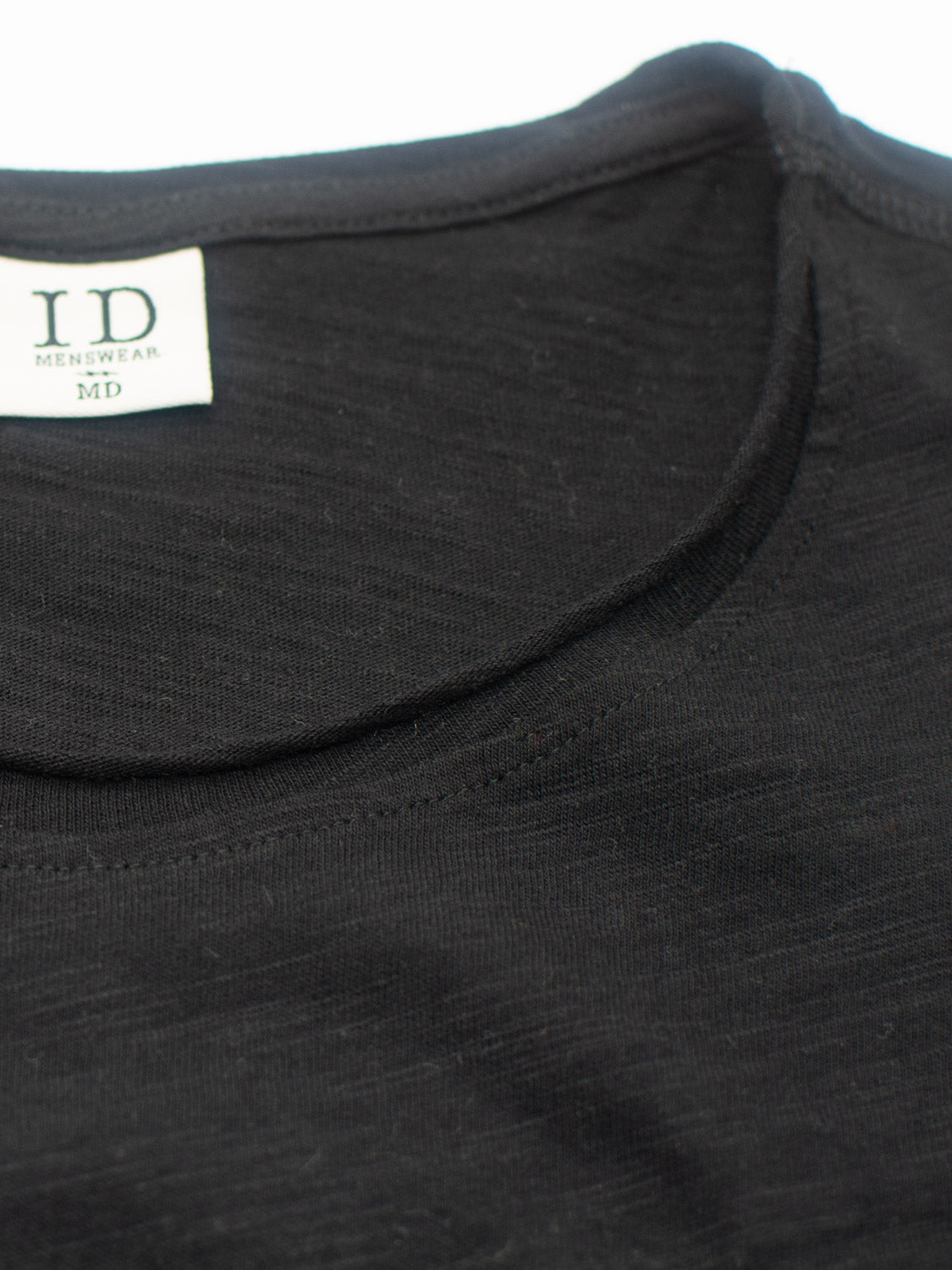 Close-up of the Da Nang Rolled Neck Slub Tee by ID Menswear. The black T-shirt, crafted from soft slub cotton with a rolled neck seam, features detailed stitching and is perfect for casual wear.