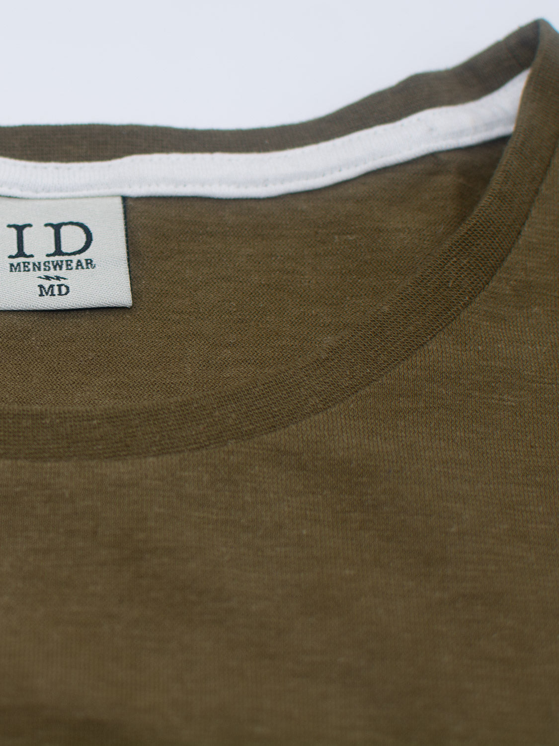 A close-up of the Dope Hemp Organic Cotton Tee in olive green by ID Menswear, crafted from sustainable fabric with a white inner collar. The neckline displays a tag with ID MENSWEAR in bold and MD below. Laid flat on a light surface, its designed for eco-conscious style.