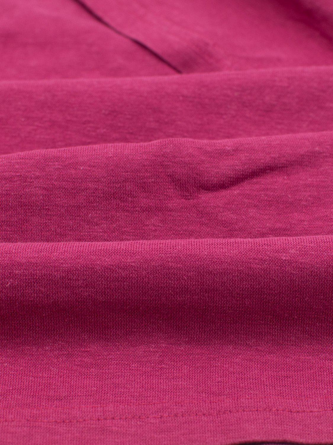 Close-up of ID Menswears Dope Hemp Organic Cotton Tee, showcasing the textured purple fabric with slight folds and varied shades under lighting. The image focuses on weave details, highlighting smooth softness—a testament to sustainable craftsmanship.