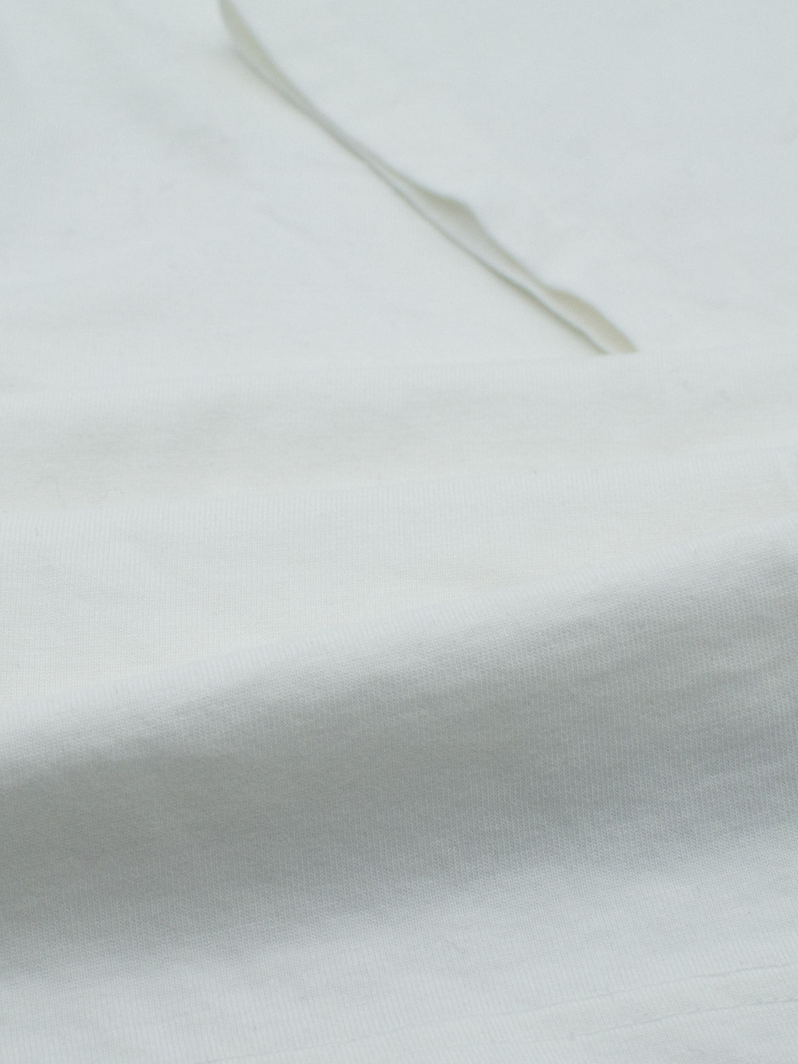 Close-up of a soft, light gray Champion Organic Cotton Henley from ID Menswear, featuring organic cotton jersey fabric with subtle texture and gentle folds.