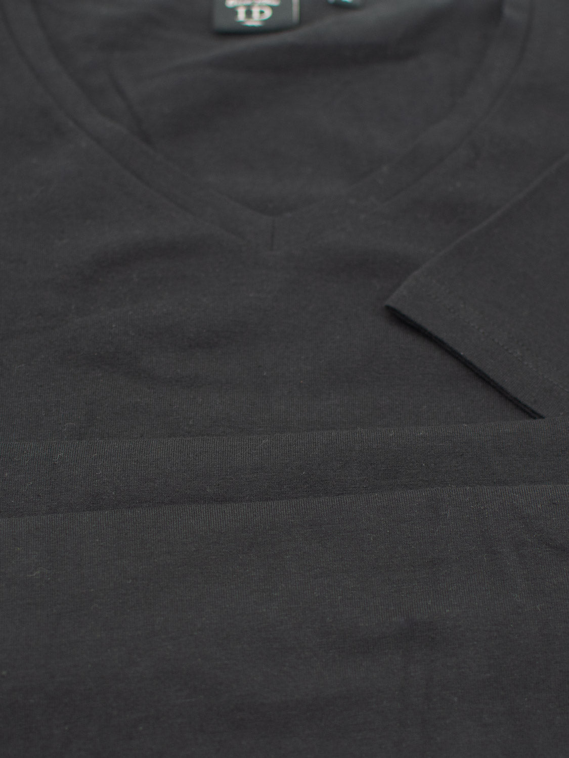 Close-up of a folded Form V Neck Tee from ID Menswear, tailored for casual events. Its texture and stitching highlight its form-fitting design. The shirt is neatly displayed with the label partially visible at the top.