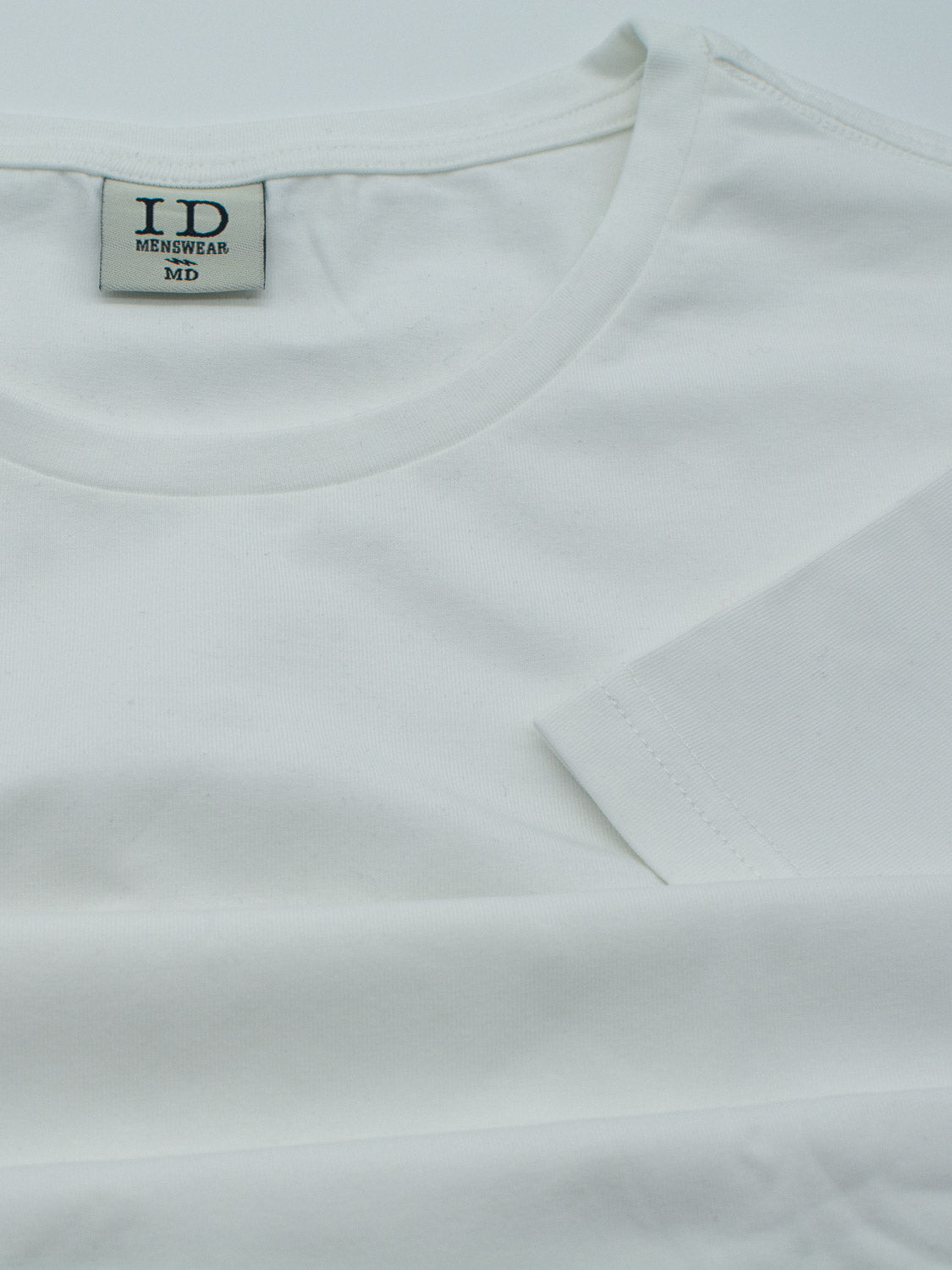 Close-up of the Form Crew Neck Tee by ID Menswear, a plain white T-shirt with a round neckline. Crafted from smooth, lightweight, and comfortable fabric, its label is visible inside the back neck area, highlighting its form-fitting design.