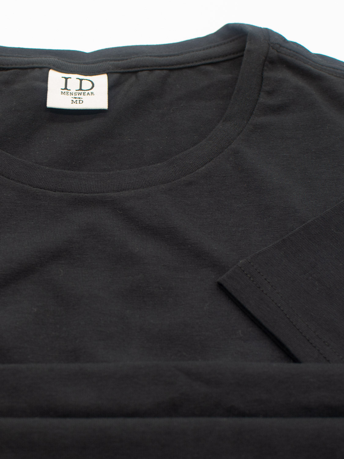 A black Form Crew Neck Tee from ID Menswear is laid flat, highlighting its comfortable fabric. The visible tag inside the collar reads ID Menswear MD. Its form-fitting design makes it an essential addition to any wardrobe.