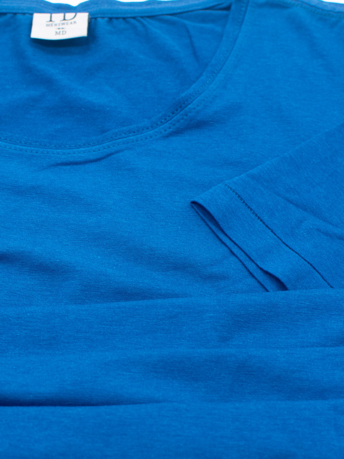 The Slay Wide Neck Bamboo Blend Tee by ID Menswear, a medium-sized blue shirt with a wide neckline and short sleeves, offers a comfortable fit. Made from organic cotton in a soft bamboo blend, its perfect for those who value style and sustainability.