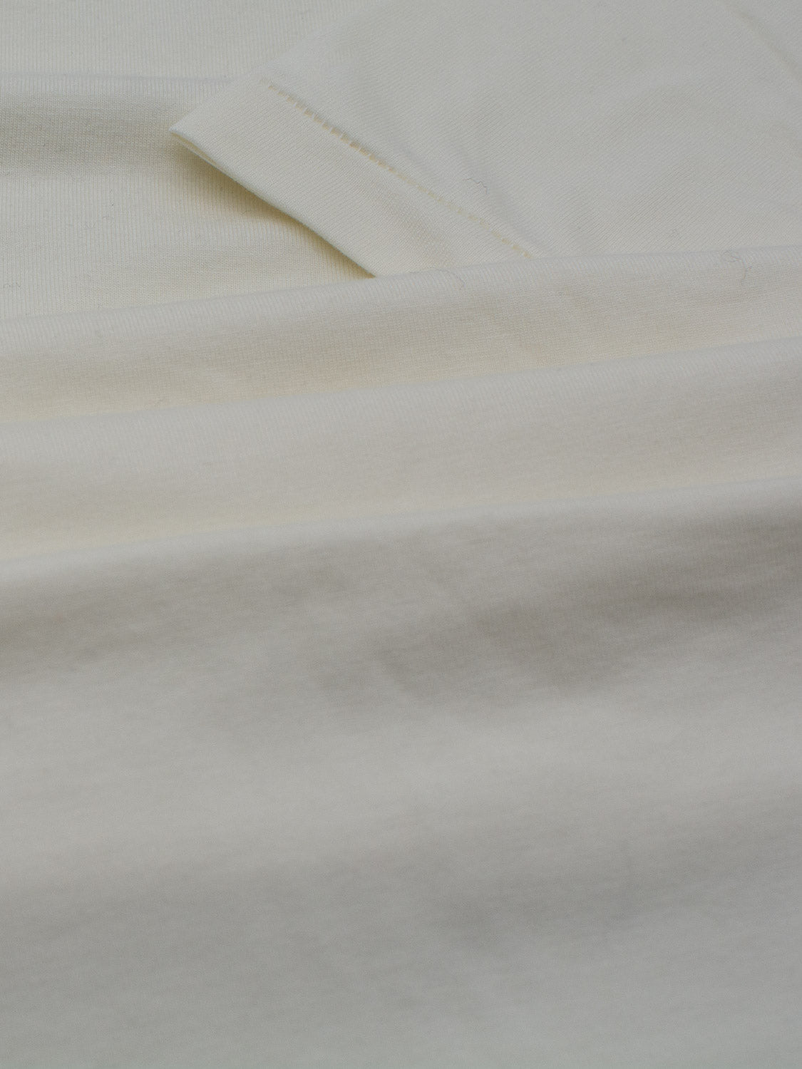 Close-up of a neatly folded Slay Wide Neck Bamboo Blend Tee by ID Menswear on a white surface. The image highlights the textures and layers, emphasizing the smooth bamboo blend material and its clean, minimalistic presentation.