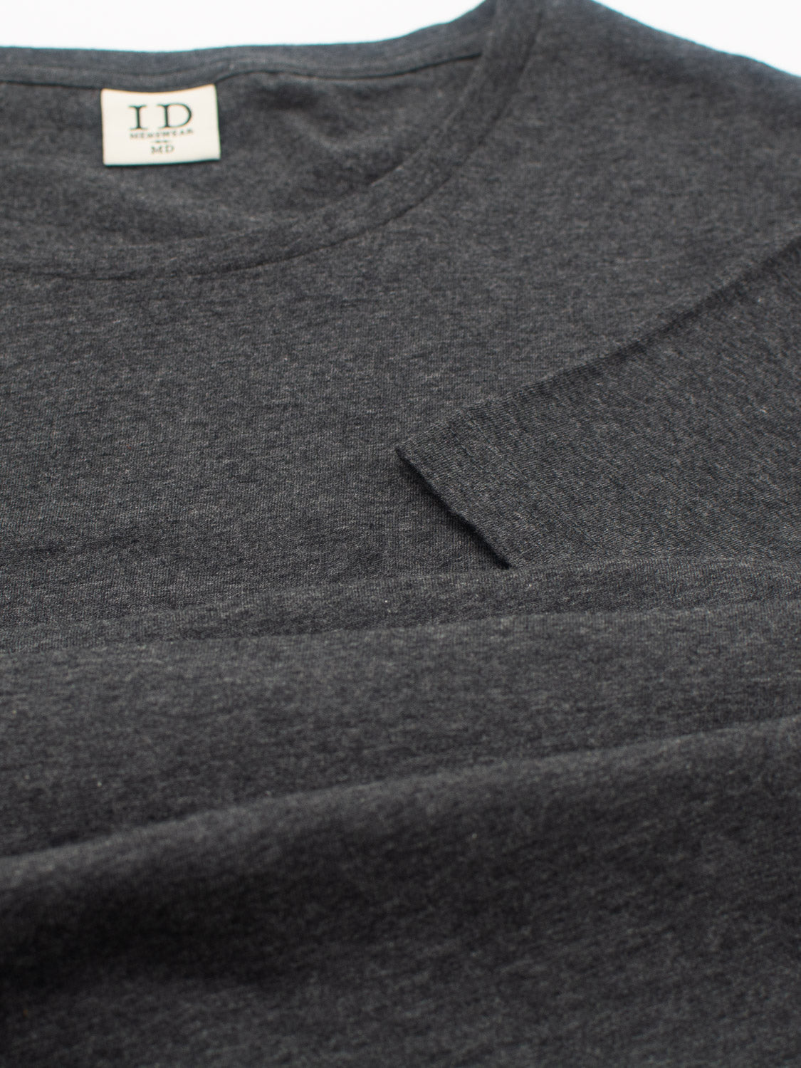 Close-up of the Outclass Cotton Crew Neck Tee in dark gray by ID Menswear, made from lightweight cotton jersey. It features a small label at the neckline reading ID M2, with soft fabric and a minimalist design.