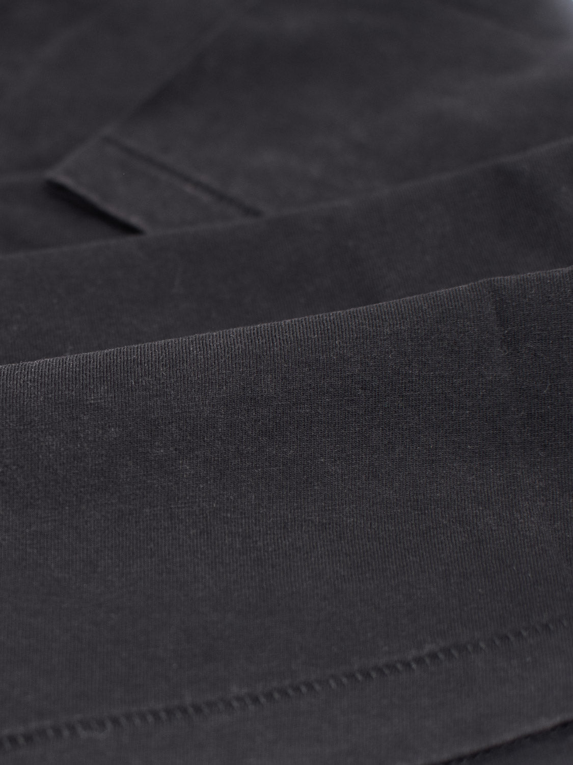 Close-up of a neatly folded stack of the Legacy Organic Cotton V Neck Tee by ID Menswear, highlighting the smooth and uniform texture of its black fabric.