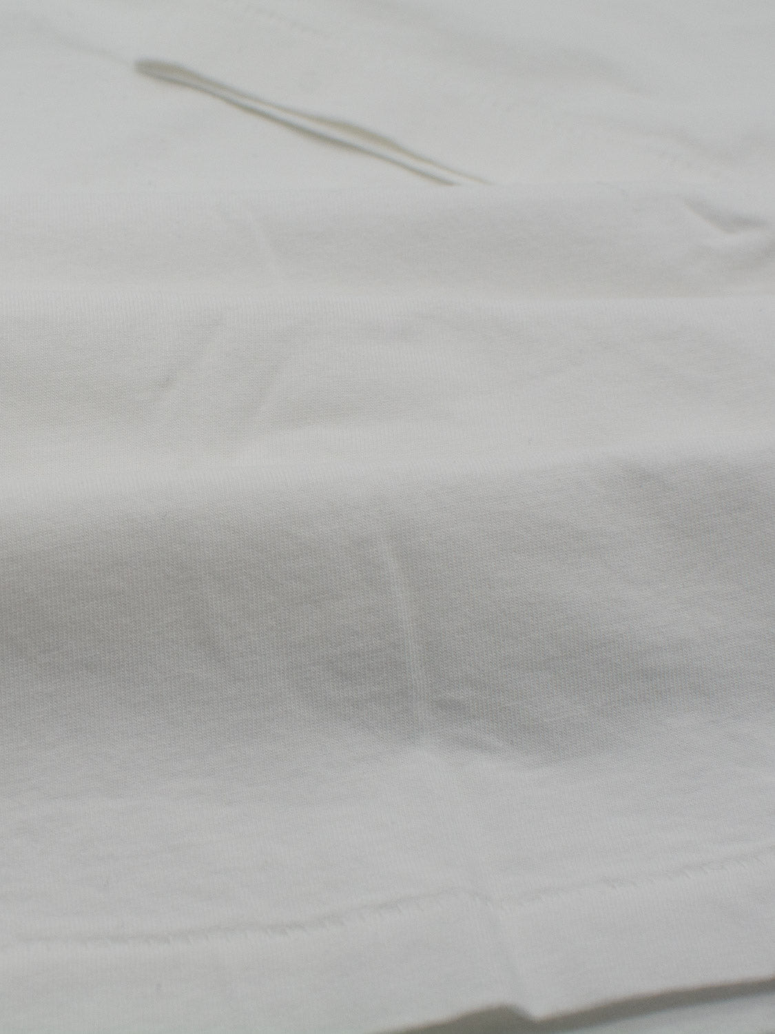 A close-up of the Legacy Organic Cotton V Neck Tee by ID Menswear shows its subtle wrinkles and soft texture, providing a vintage look.