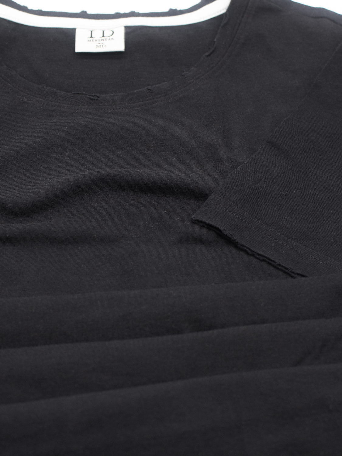 Close-up of a black Trekker Tattered Crew Neck Tee by ID Menswear, showcasing a round neckline and visible label with size info. Made from organic cotton, the fabric highlights its smooth texture and minimalist design.