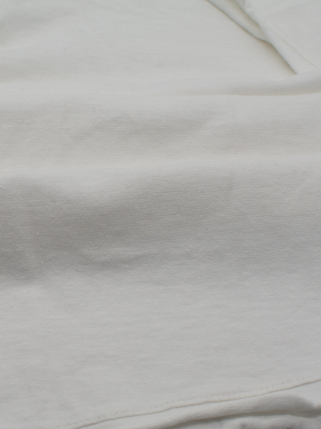 Close-up of ID Menswears Legend Hemp Cotton Rolled Neck Henley, revealing its soft, textured organic cotton fabric with slight folds and gentle shadows that highlight the weave pattern.