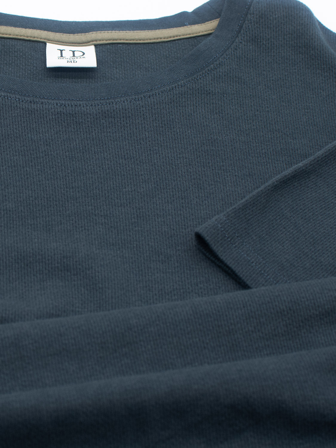 A folded dark gray Urban Honeycomb Mesh Tee by ID Menswear features long sleeves, a round neckline, and a visible tag near the collar, crafted from a breathable bamboo-organic cotton blend.