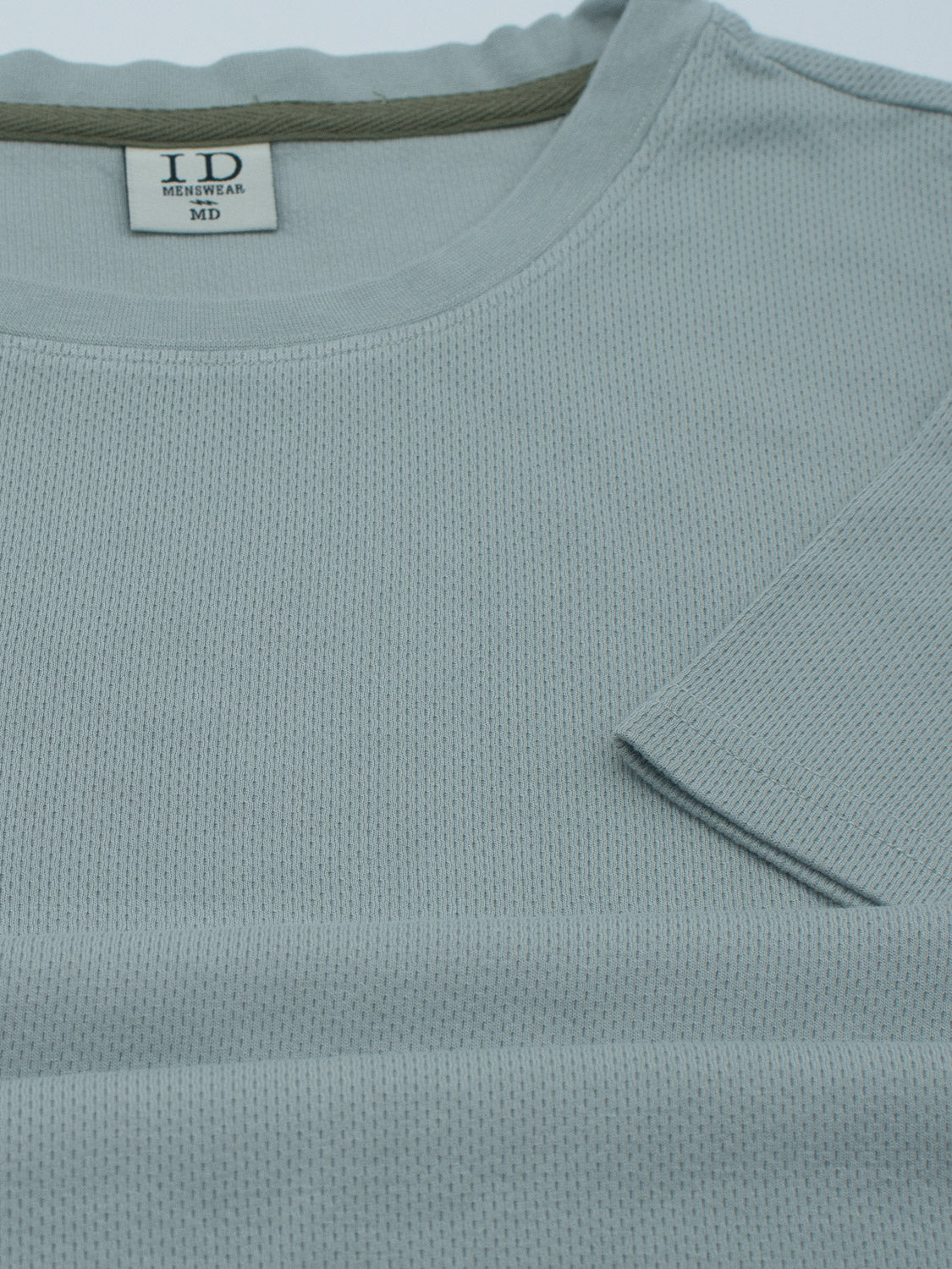 Light blue Urban Honeycomb Mesh Tee by ID Menswear, crafted from a bamboo-organic cotton blend, features a ribbed design with a sewn pocket detail on the chest and a round neckline for comfort. This breathable tee elevates everyday wear. Inside label reads MD.