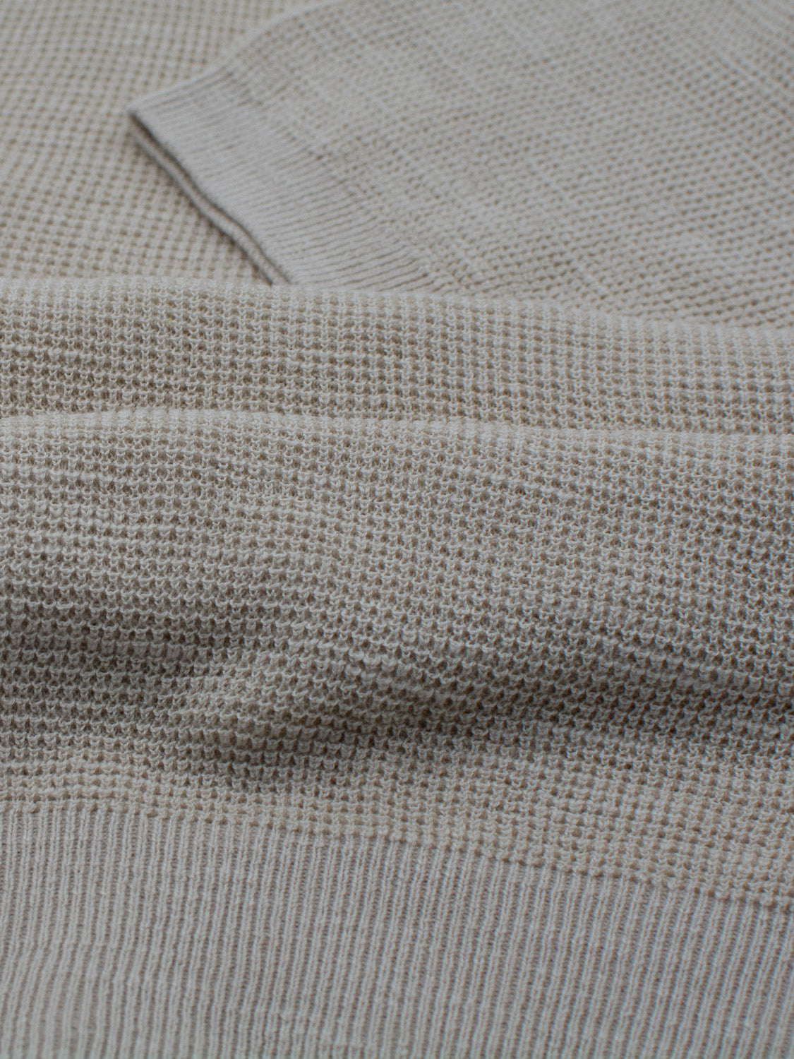 Close-up of ID Menswears Ankara Linen Blend Waffle Knit Polo in light gray, highlighting its lightweight and textured fabric. The cozy yet breathable knit features detailed stitches and subtle, uniform patterns reminiscent of a structured waffle design.