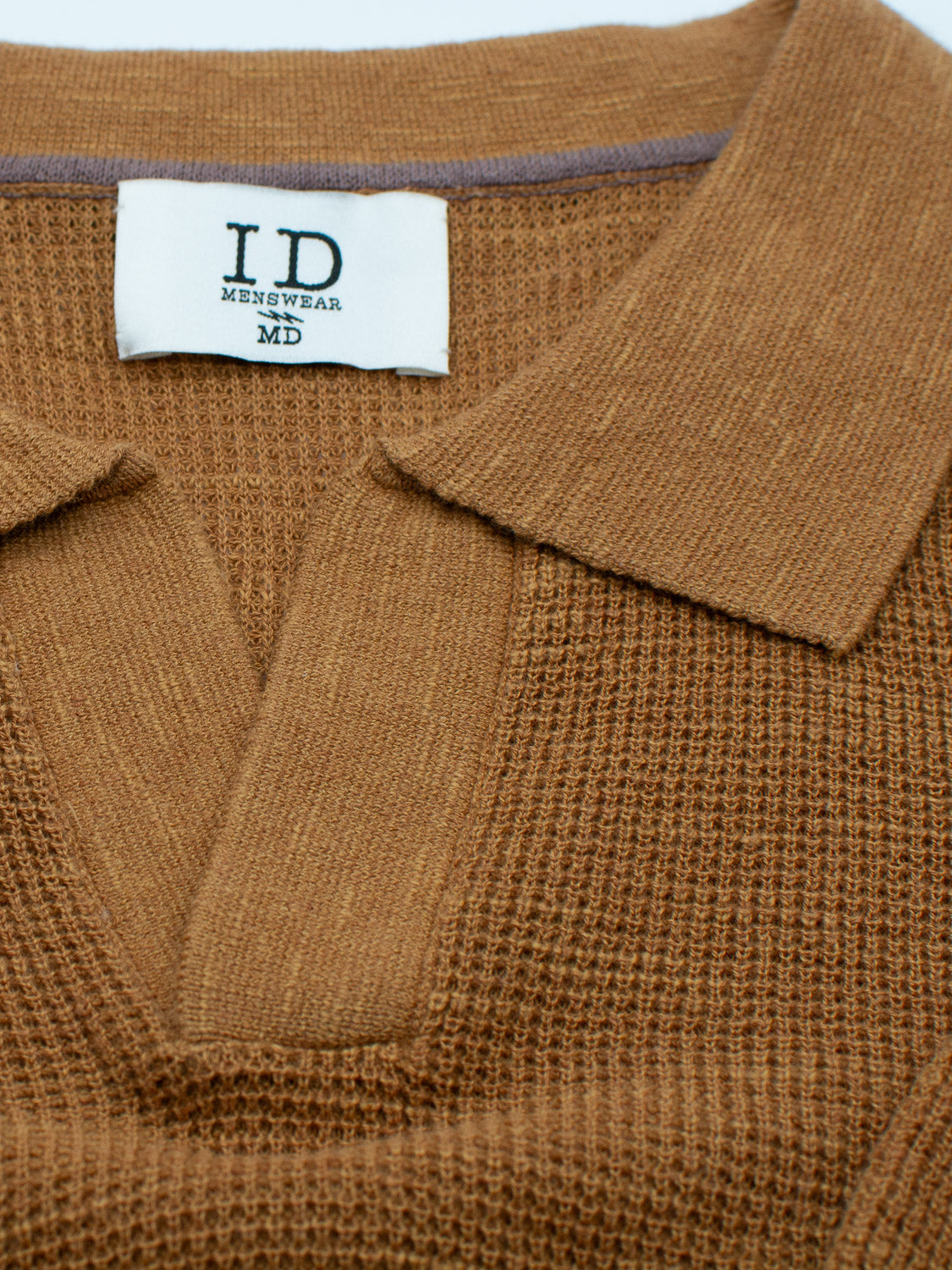 Close-up of a brown Ankara Linen Blend Waffle Knit Polo featuring a collar and lightweight, breathable texture ideal for warm weather. The label inside reads ID Menswear.