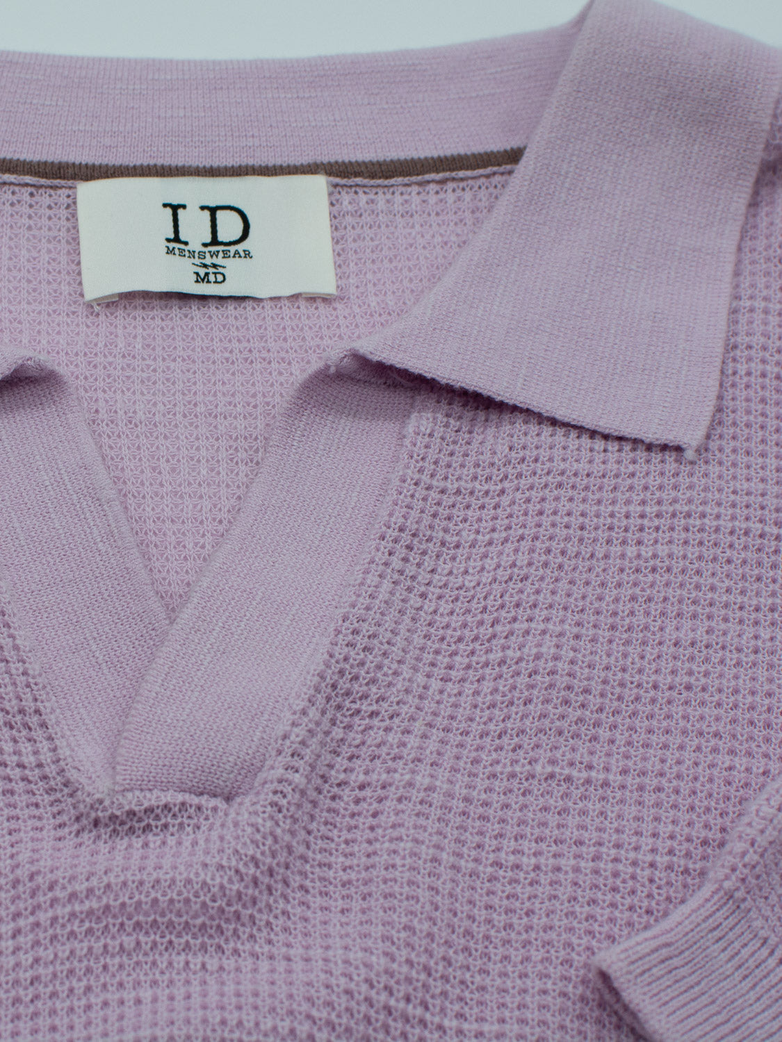 Close-up of the Ankara Linen Blend Waffle Knit Polo by ID Menswear, showcasing a lavender texture with a pointed collar and deep neckline. Its lightweight, breathable fabric features a waffle-like pattern for added depth, perfect for warm weather. Size: MD.
