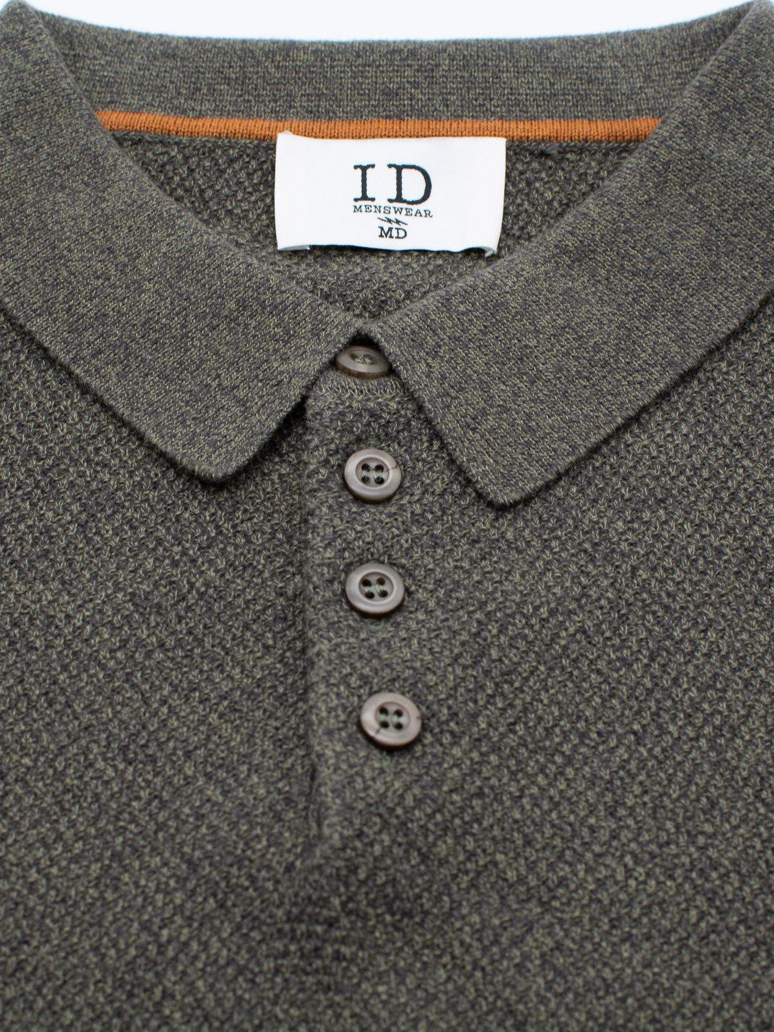 Close-up of a textured dark gray collared shirt with four buttons. A white label inside the collar reads ID Menswear MD in black text. This Austin Knitted Cotton Polo provides a breathable fit, ideal for casual wear.