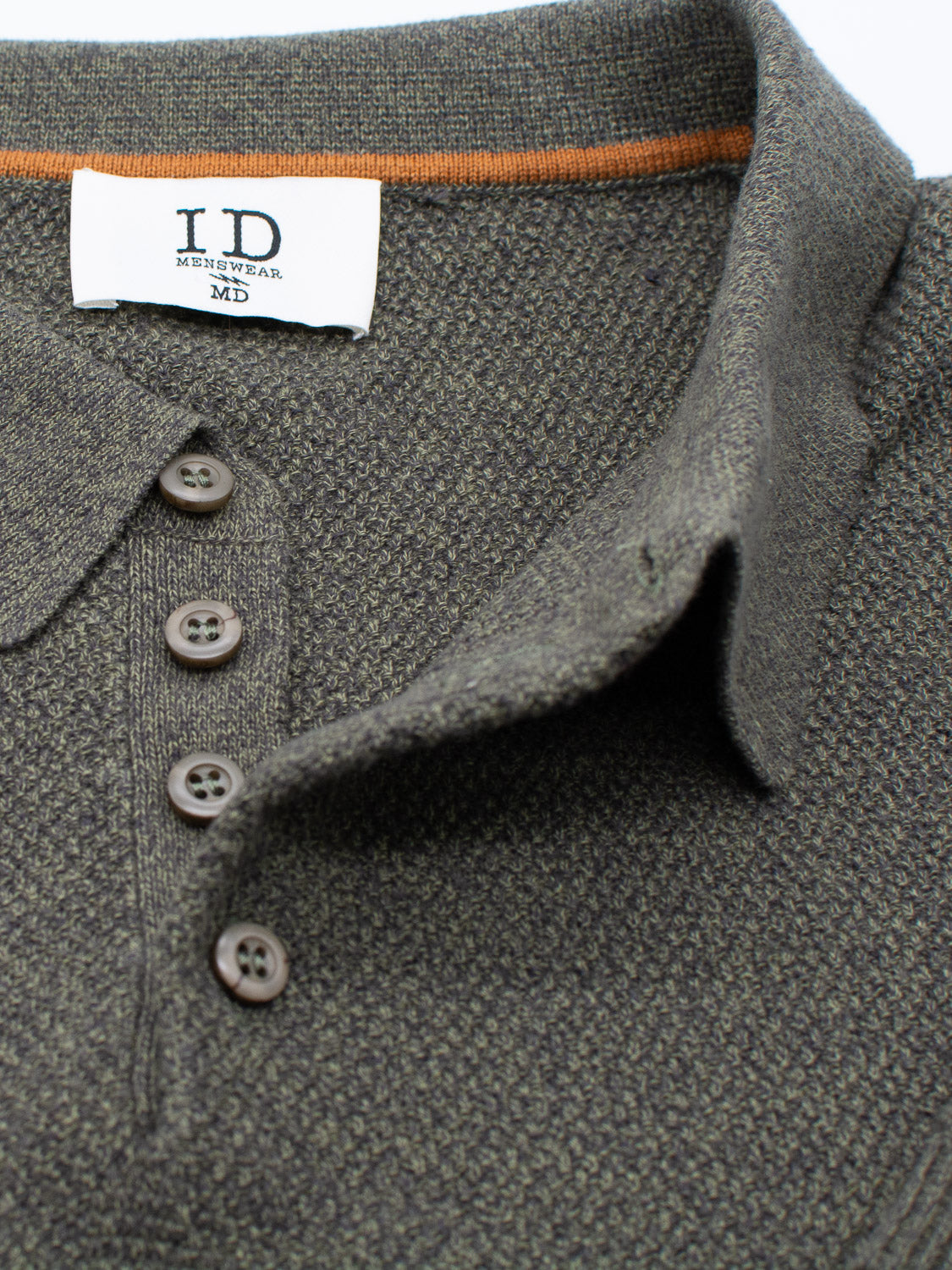 Close-up of the textured dark gray Austin Knitted Cotton Polo with four brown buttons and a folded collar. Inside, ID Menswear MD reads in black text, and an orange trim offers breathability, making it ideal for casual wear.