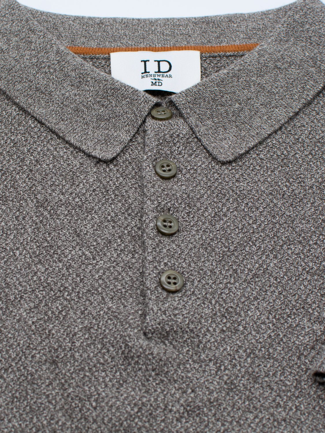Close-up of the Austin Knitted Cotton Polo by ID Menswear, featuring a gray textured cotton-knit with a folded collar and four brown buttons down the placket. The white label at the neckline offers a breathable fit suited for casual wear.