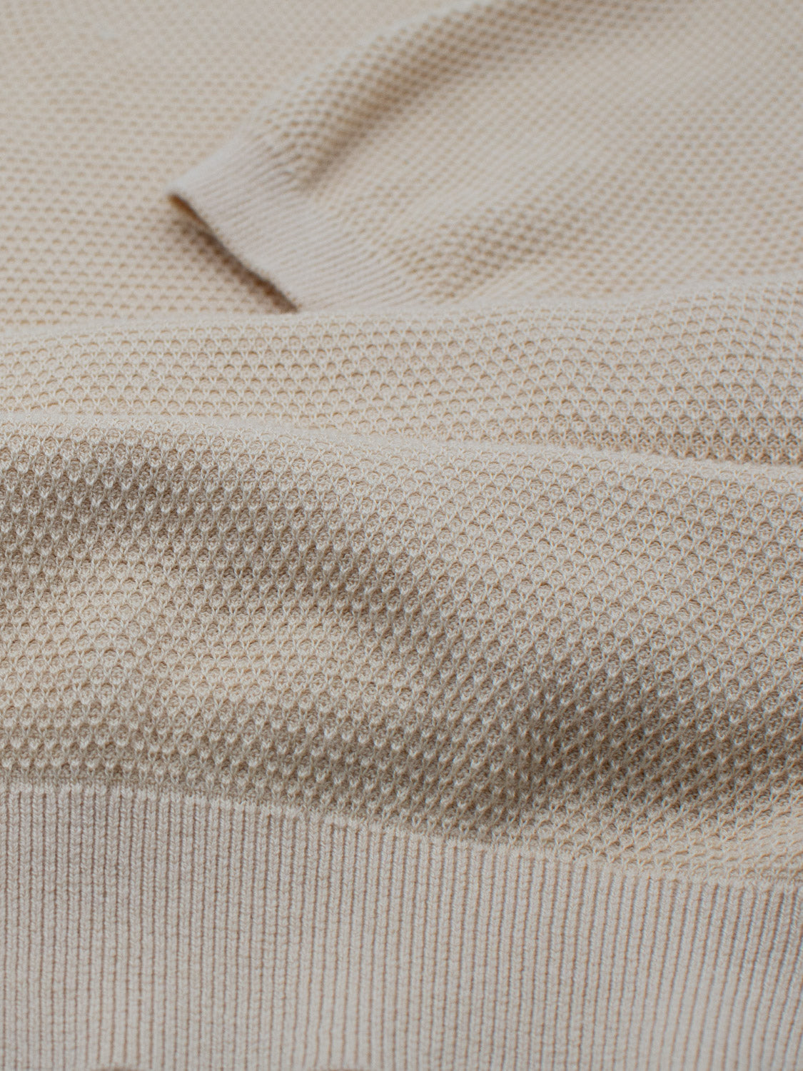 Close-up of ID Menswears Monaco Knitted Cotton Polo in beige featuring a textured honeycomb pattern. The fabric showcases small, raised bumps, with a smooth, soft appearance, highlighting fine craftsmanship and detail.