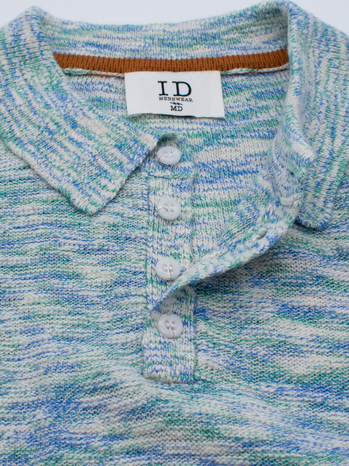 Close-up of the Miami Reverse Knit Cotton Polo by ID Menswear. This casual shirt blends blue, green, and white hues and features a knit collar, four-button placket with white buttons, and a sewn ID MENSWEAR MD label inside the collar for style and breathability.